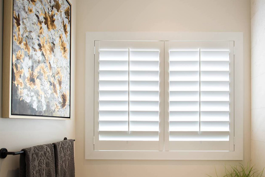 Let the sunshine in your bathroom with elegant white Polywood shutters. White Polywood shutters in a small bathroom full of light.
