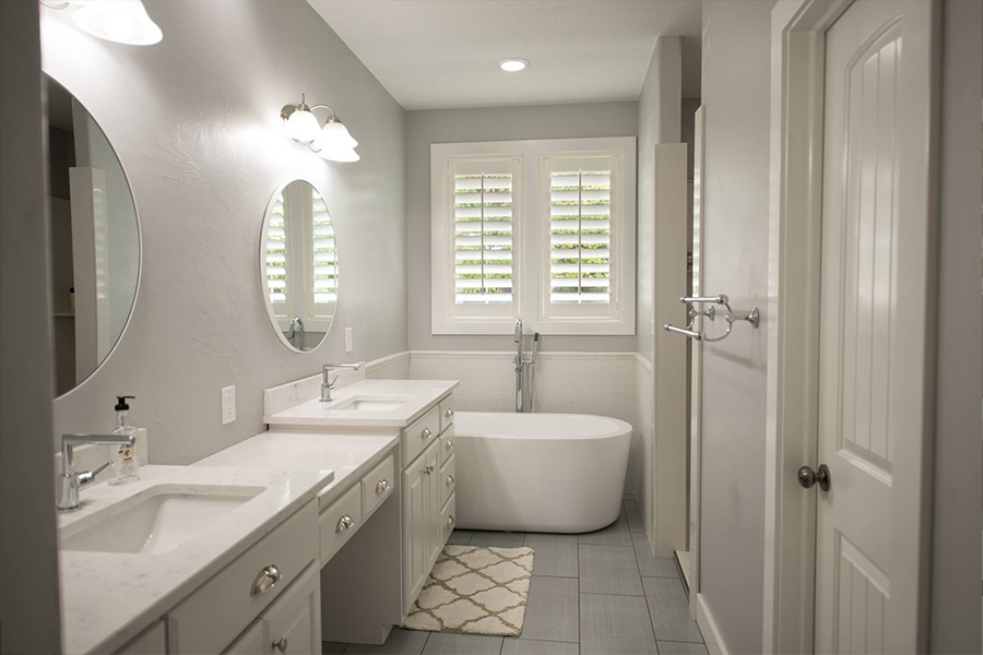 White Polywood shutters are timeless and classy for a modern styled bathroom. White and gray bathroom with one white Polywood shutters on a window above a modern style bathtub.