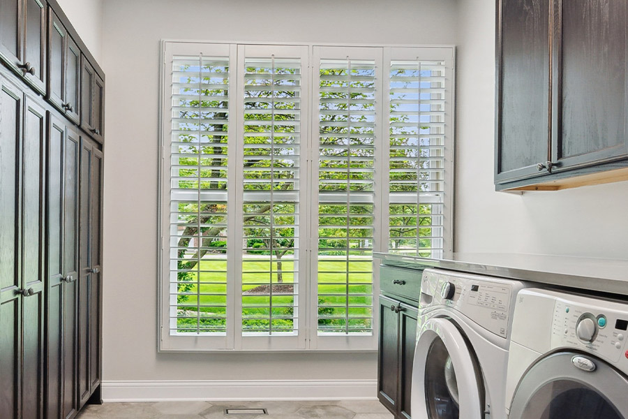 Find the perfect level of natural light for your Fort Myers laundry room with interior shutters. White Polywood shutters letting light through a laundry room window