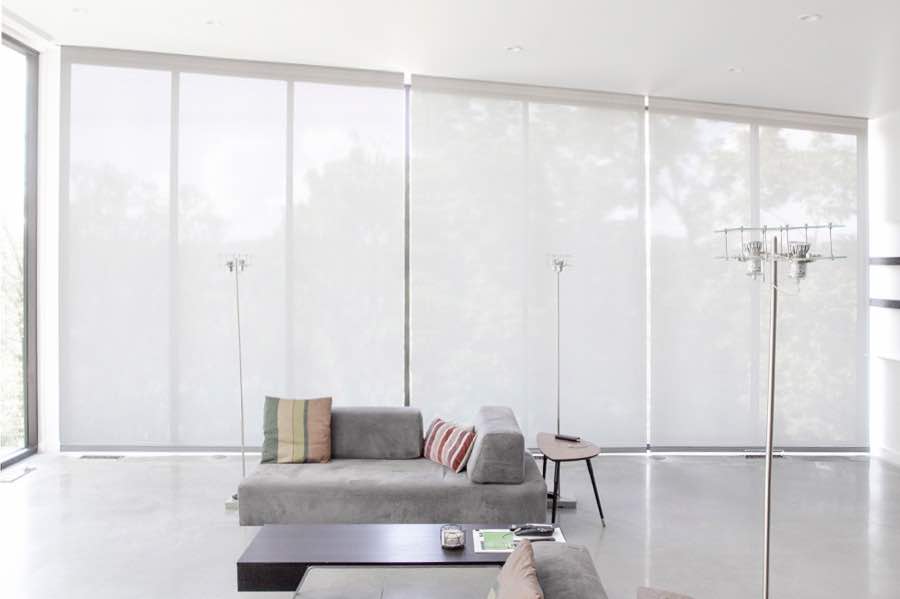 Motorized window shades make controlling natural light effortless in your Fort Myers great room. White motorized shades on a wall of tall great room windows