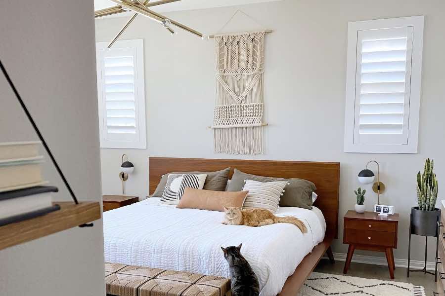 Invest in new window treatments when you need better light control or something safer for pets. Two cats in a bedroom with Polywood shutters on the windows