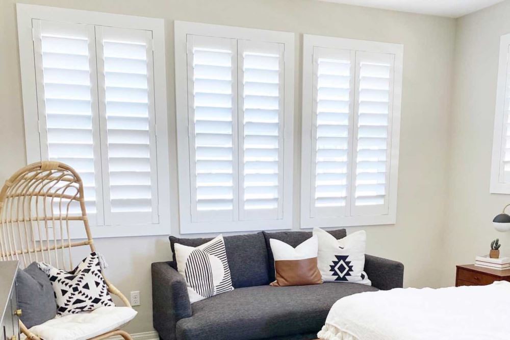No matter what's in style, Polywood shutters will match your decor and make your home more cozy and energy efficient. white Polywood shutters on windows in a stylish bedroom