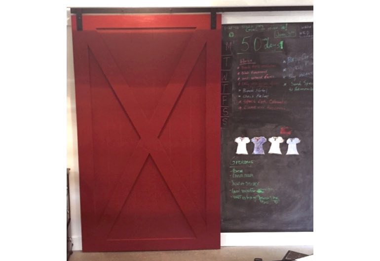 Red barn door with black track next to chalkboard