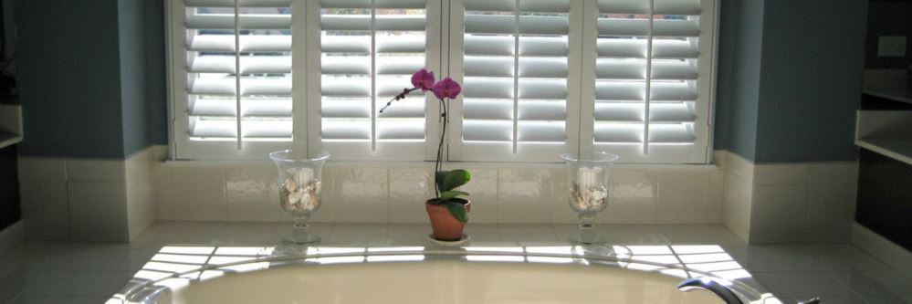 White Polywood shutters above a bath tub.