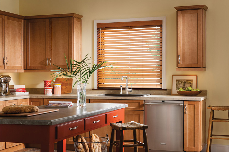 Waterproof faux wood blinds are durable and give you privacy and light control in your Fort Myers kitchen. Dark faux wood blinds above a kitchen sink